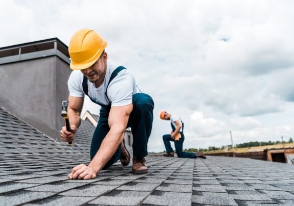 selective-focus-of-handyman-holding-hammer-while-repairing-roof-near-coworker.jpg